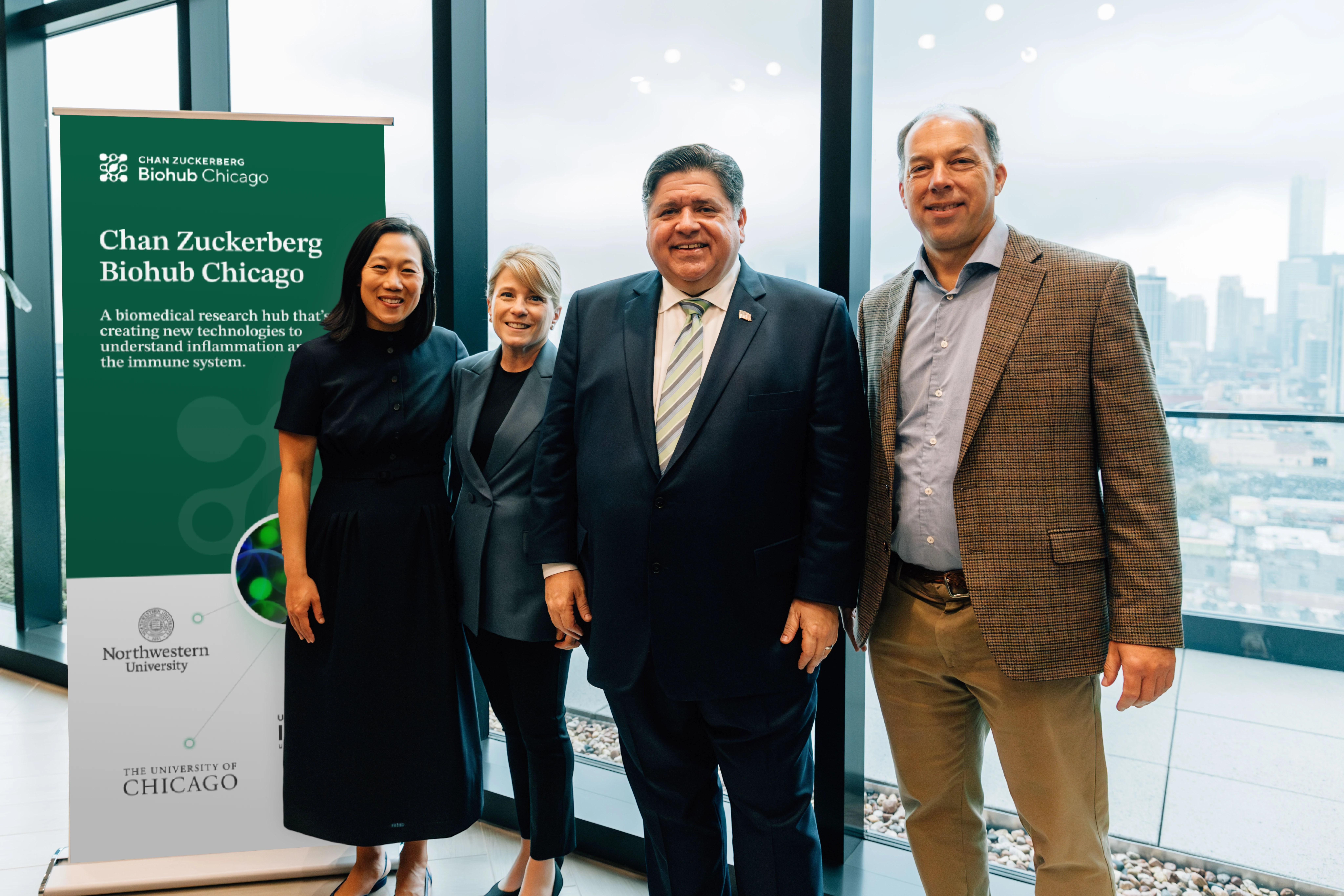 Four people standing together in front of a banner.